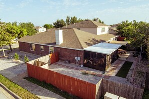 A residential house with a sloped roof, a fenced backyard, and a small front yard.
