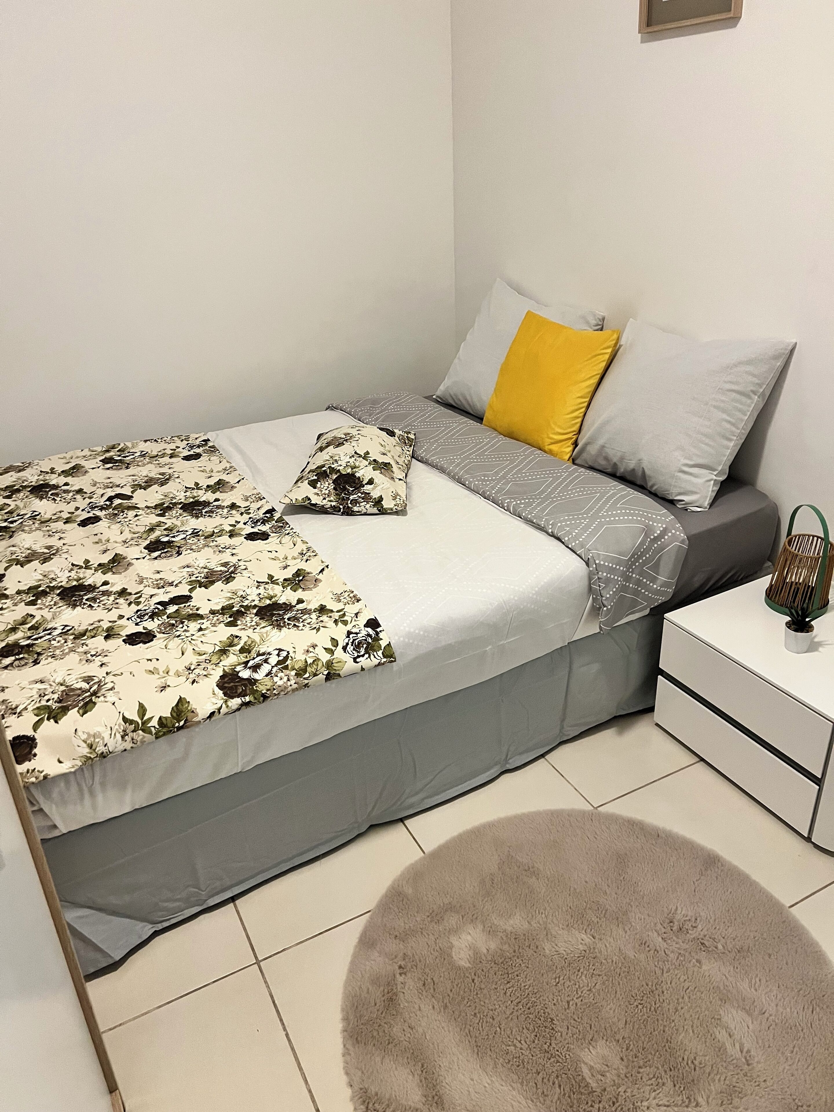 Une chambre à coucher bien rangée, avec un lit, des tables de chevet et un petit tapis.