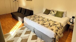 Un dormitorio con una cama grande, un sofá y una mesita de noche con una lámpara.