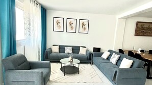 A modern living room with two grey sofas, a coffee table, and a dining area with chairs.