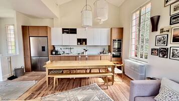 Une cuisine moderne avec des meubles en bois, un four encastré et un coin repas comprenant une table et des bancs en bois.
