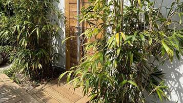Une terrasse en bois mène à un bâtiment blanc doté d’une porte en bois.