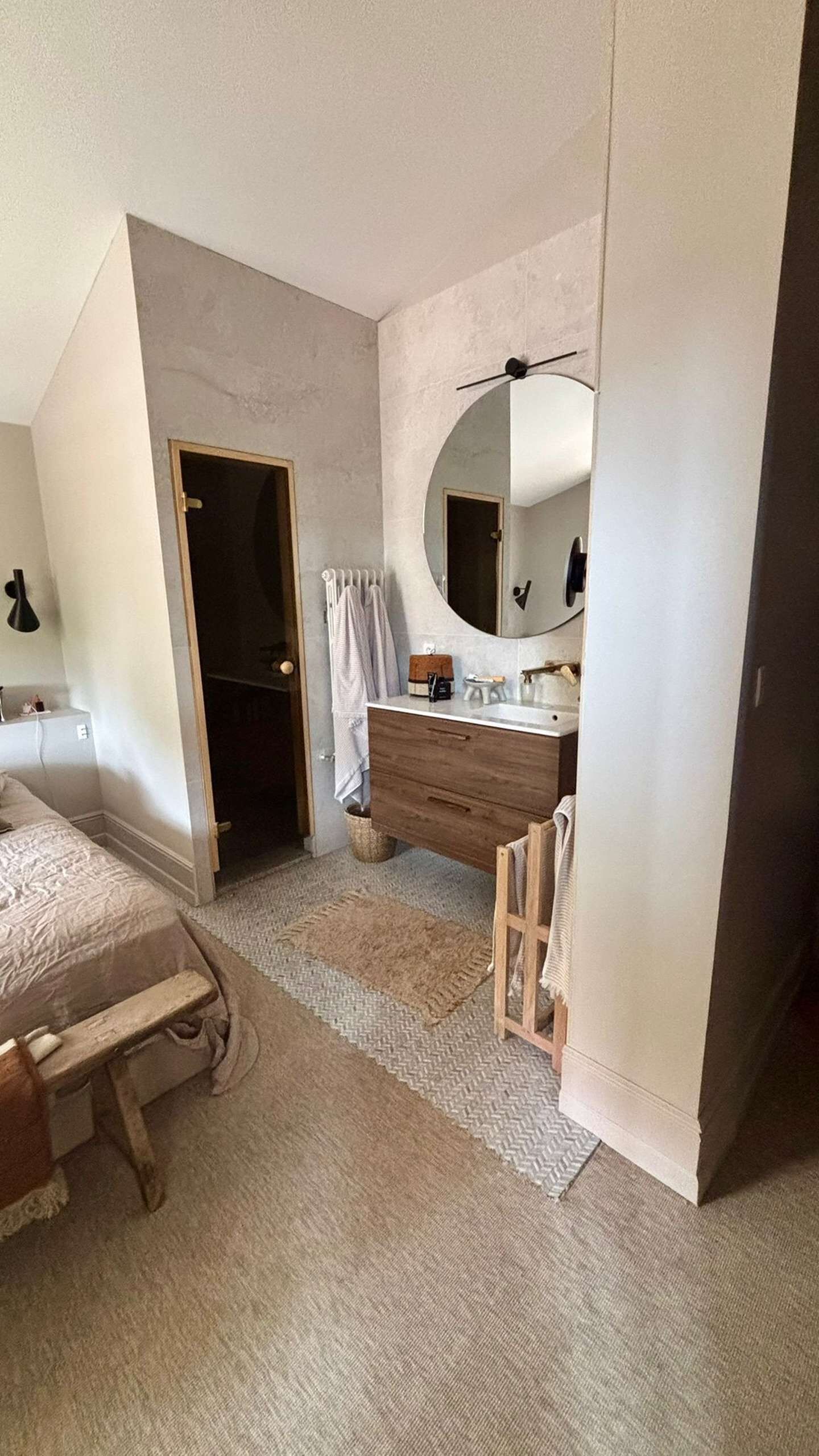 Ein Schlafzimmer mit einem Bett, einer Holzkommode, einem runden Spiegel und einem Deckenventilator.