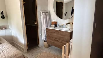 Ein Schlafzimmer mit einem Bett, einer Holzkommode, einem runden Spiegel und einem Deckenventilator.