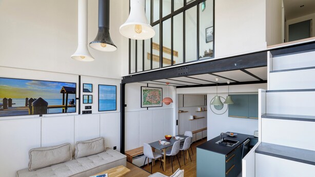 A modern interior with a sofa, dining table, and kitchen area.