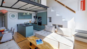 A modern kitchen with teal cabinets, a central island, and pendant lighting.