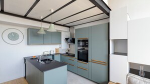 A modern kitchen with a central island, built-in appliances, and a clock on the wall.