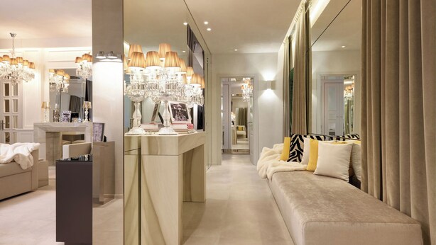 A modern hotel room with a large mirror, a vanity with a chandelier, a sofa with patterned cushions, and a well-lit hallway. - Luxurious 3 Bedroom Apartment near Pantheon (Roma)