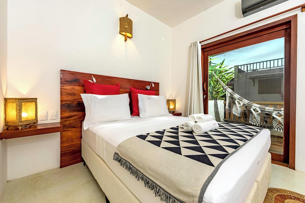 A neatly made bed with a geometric patterned blanket, a wooden headboard, and two bedside lamps.