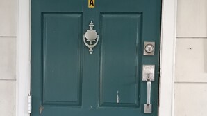 Una puerta color turquesa con un panel de vidrio y un cerrojo.