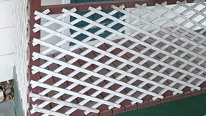 Una casa con puerta verde, ventana blanca y cerca de encaje blanco.