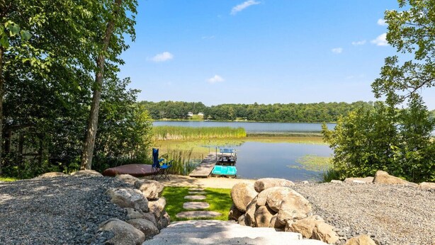 A lakeside view with a dock, a blue chair, and a small boat. - Maple Lake Hideaway! (Longville)