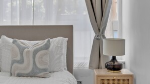 A bedroom with a bed, a bedside lamp, and a window with curtains.