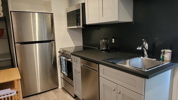 A compact kitchen with stainless steel appliances, a microwave, and a sink.