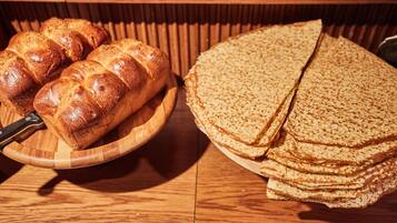 A wooden table with a loaf of bread and a stack of flatbreads.