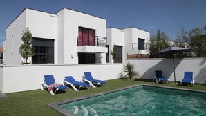 A modern building with a swimming pool, blue lounge chairs, and a red curtain on one window. - Villa Luxe 8p | Piscine & Plages à Pied (Anglet)