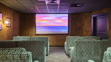 Een bioscoopzaal met gestreept groene stoelen, een groot scherm waarop een zonsondergang wordt getoond, en een projector bevestigd aan het plafond.