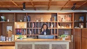 A reception desk with a wooden finish, a Dell computer, and a variety of books and decorative items on shelves. - T3 familial 6 pers. | Train pour Paris à 5 min (Levallois-Perret)