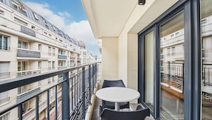 A balcony with a table and chairs, overlooking a residential building with balconies. - T3 familial 6 pers. | Train pour Paris à 5 min (Levallois-Perret)