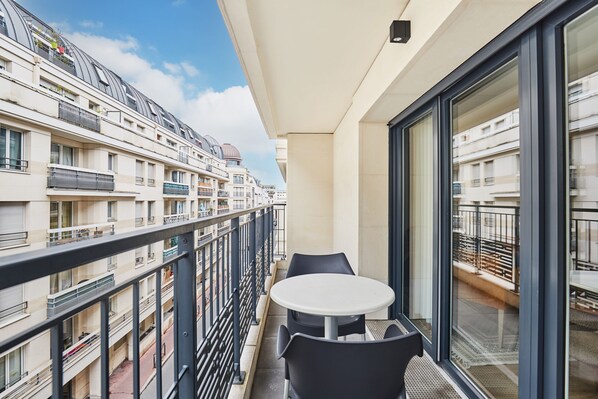 Un balcón con mesa y sillas, con vistas a un edificio residencial con balcones.