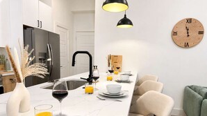 A modern kitchen with a white countertop, black faucet, and a wooden clock on the wall.