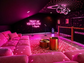 A room with a pink sofa, a microphone stand, and a neon sign.
