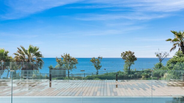 A clear view of a swimming pool with a wooden deck, surrounded by palm trees and a view of the sea. - Sapphire | Sea view - pool - terrace (Estepona)