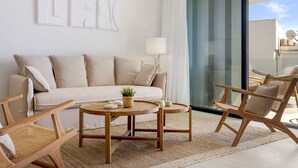 A modern living room with a sofa, two wooden chairs, a small round table, and a potted plant. - Sapphire | Sea view - pool - terrace (Estepona)