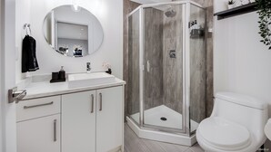 Une salle de bain moderne avec une douche à parois de verre, un lavabo blanc et des toilettes.