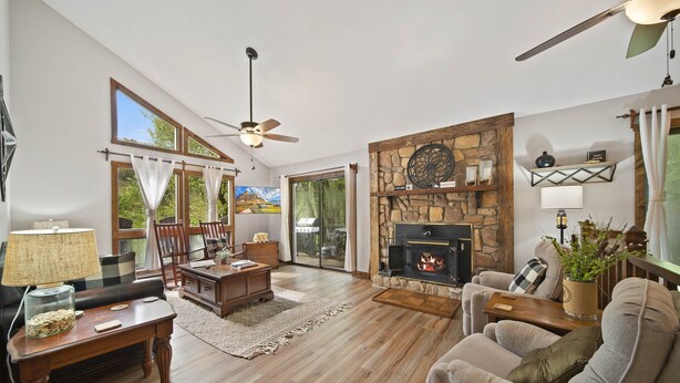 A spacious living room with a fireplace, wooden flooring, and large windows.