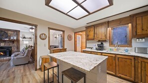 A kitchen with wooden cabinets, a marble countertop, and a stone fireplace.