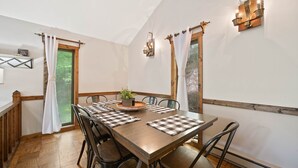 A dining area with a wooden table, black chairs, and checkered placemats.