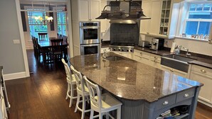 A kitchen with a large island, built-in appliances, and a dining area with a view.