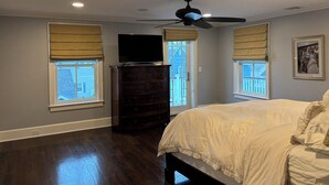 A bedroom with a bed, a dresser, a ceiling fan, and two windows with blinds.