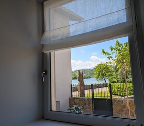 Enjoy a serene view of the lake from the comfort of your room, with a tree-lined path and stone wall in the foreground.