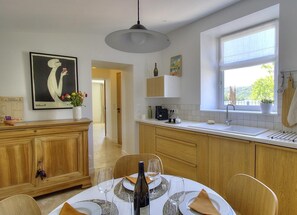Enjoy a meal at the dining table, surrounded by a kitchen with oven, countertop, and utensil rack.