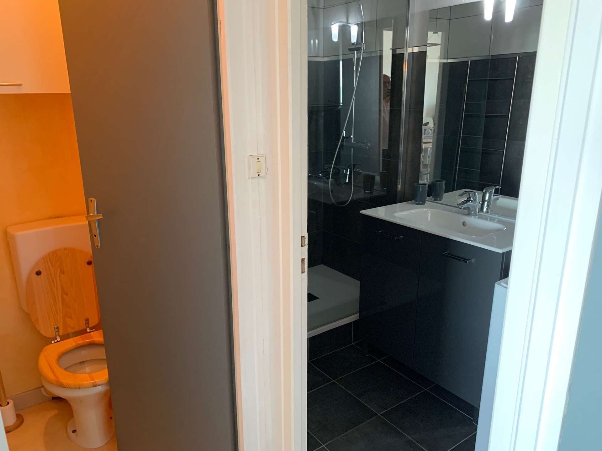 A modern bathroom with a toilet, a shower, and a sink.