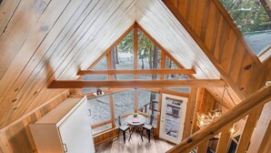 Una cabaña de madera con techos altos, un comedor y una cocina.