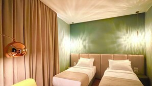 A hotel room with two beds, a yellow armchair, and a large window with curtains. - The MONT BOUTIQUE HOTEL (Shkodër)