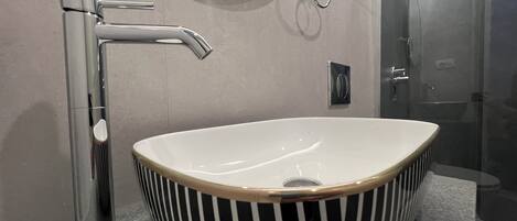 Ein modernes Badezimmer mit einem schwarzen und weißen Streifen-Waschbecken, einem Chrom-Wasserhahn und einem Spiegel über dem Waschbecken.