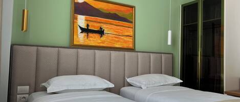 A hotel room with two beds, a large painting of a sunset over water, and a sliding glass door closet.