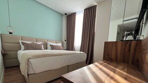 A modern bedroom with a large bed, a wooden nightstand, and a mirror. - The MONT BOUTIQUE HOTEL (Shkodër)