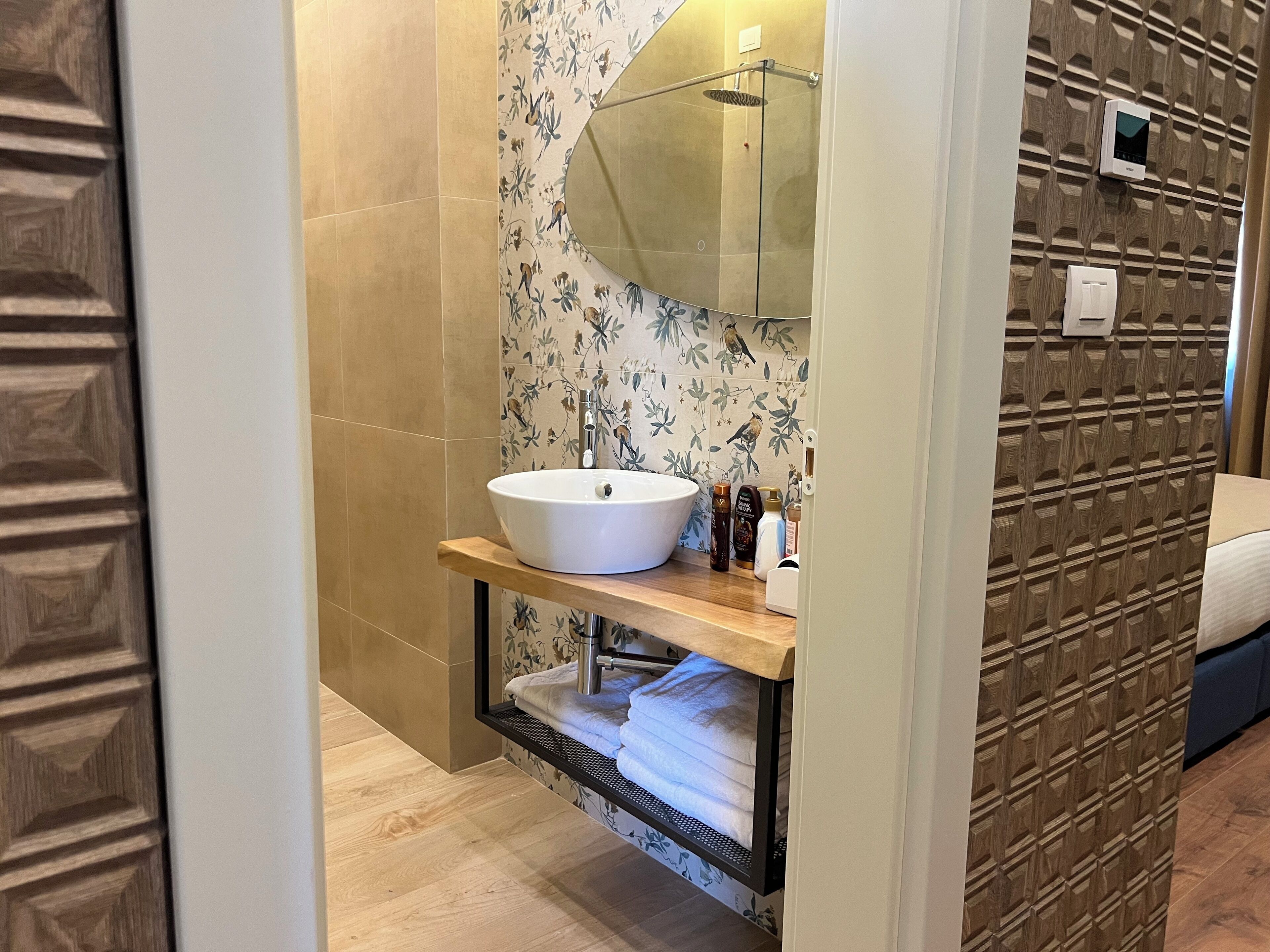 A bathroom with a wooden vanity, a white sink, and a shower with a glass door.