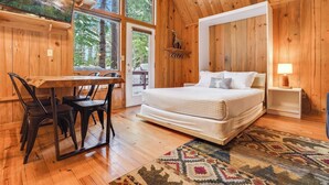 A wooden cabin bedroom with a bed, a desk, and chairs. - Beautiful Cabin With Partial Views of Mt. Adams (Trout Lake)