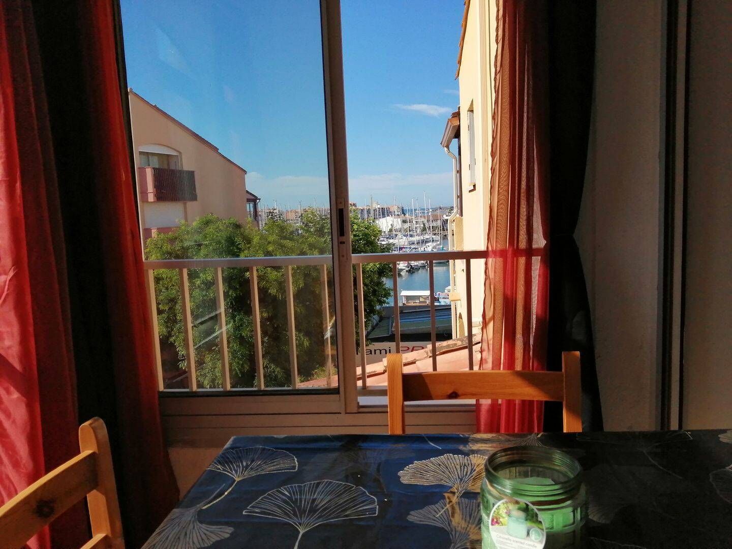 Un balcón con vista a un puerto deportivo, una mesa con mantel y una silla.