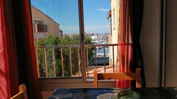 Un balcón con vista a un puerto deportivo, una mesa con mantel y una silla.