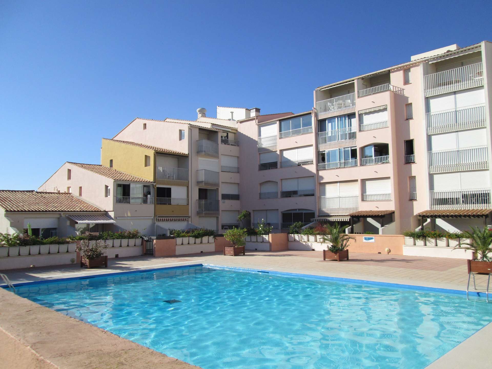 Una piscina rodeada de edificios residenciales de varios pisos con balcones.