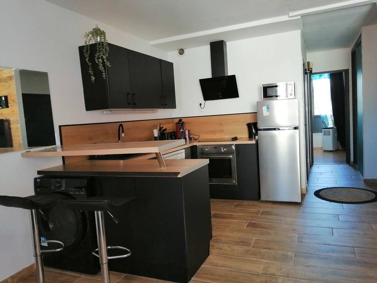 Una cocina moderna con una isla central, armarios negros, microondas y refrigerador.