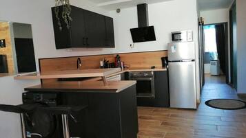 Una cocina moderna con una isla central, armarios negros, microondas y refrigerador.
