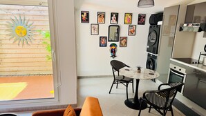 A modern kitchen with a built-in oven, a dining area with a round table and black chairs, and a wall decorated with various posters. - Stylish City Pad – Walk to All (Bergerac)